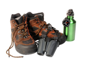hiking boots with binoculars compass and water bottle